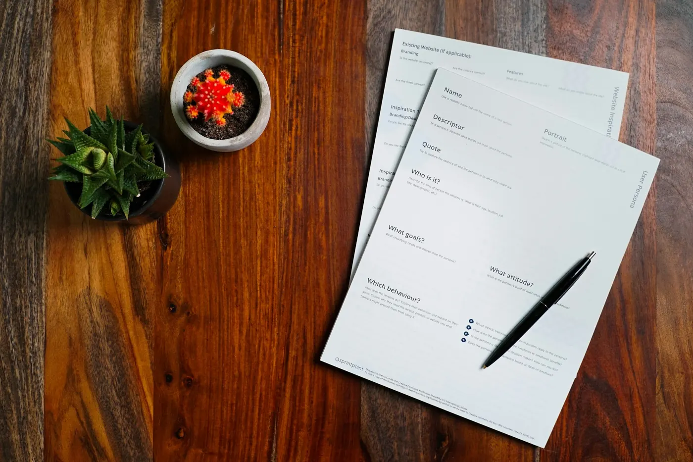Taula de despatx de fusta amb documents i una ploma